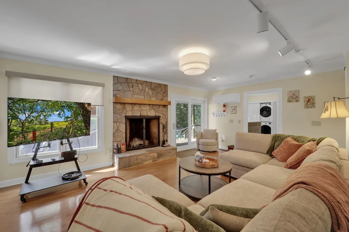 House living room with a sectional sofa, brick fireplace, television, and large window